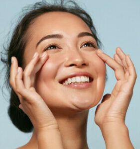 a lady smiling and touching her face with both hands